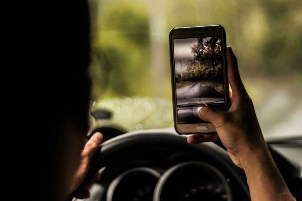 man uses his phone to take a picture while driving